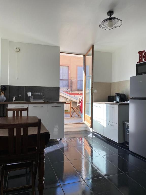 a kitchen with white cabinets and a table in it at Appartements VIZILLE GRENOBLE - Route Napoleon in Vizille