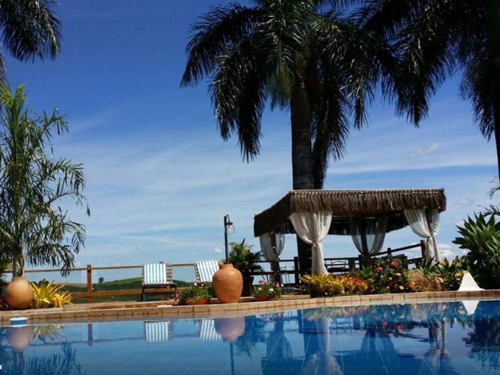 una piscina con una palmera en el fondo en Pousada e Restaurante Caminhos do Bom Café en Jacutinga