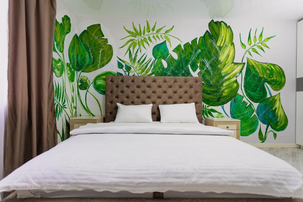 a bedroom with a large bed with green plants on the wall at Relax Apartments in Sumy