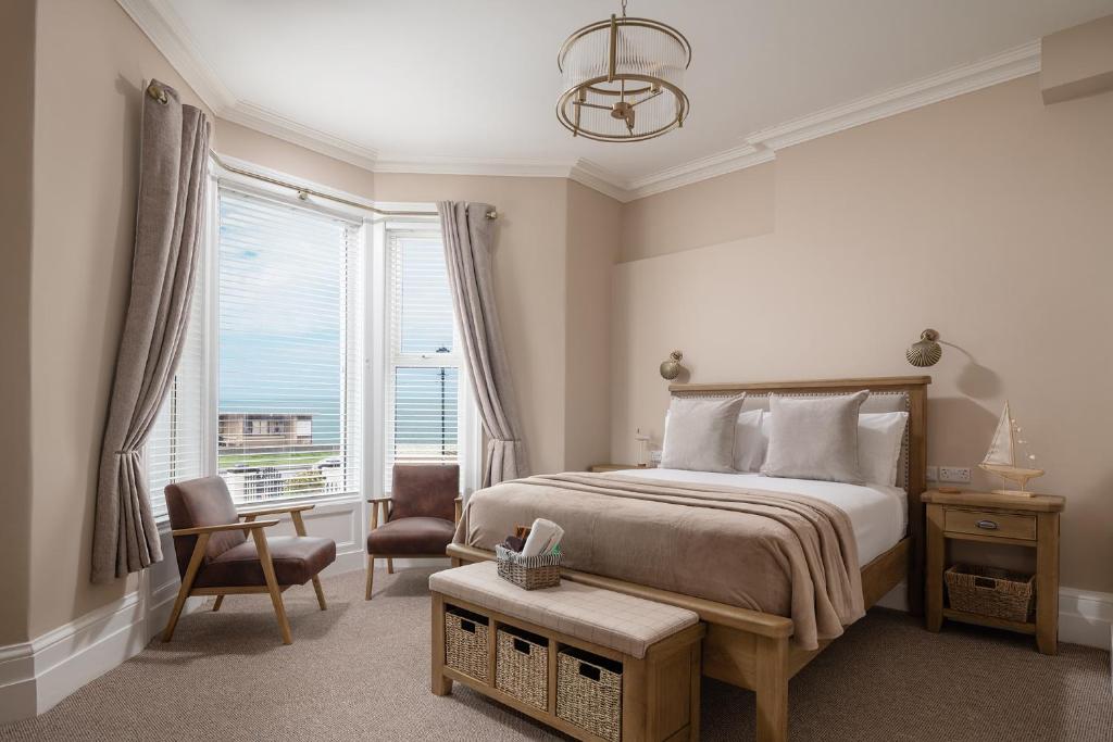 a bedroom with a bed and a chair and a window at Pebble House in Llandudno