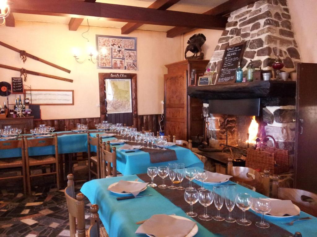 uma sala de jantar com mesas azuis e uma lareira de pedra em Auberge La Bergerie em Sainte-Marie-de-Campan