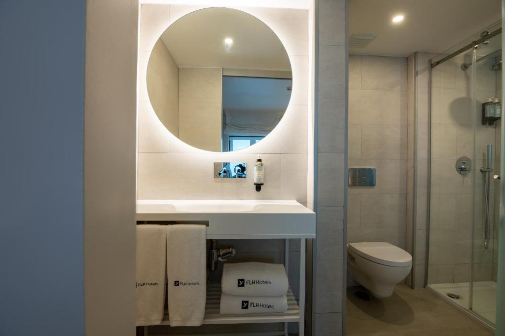 a bathroom with a sink and a mirror and a toilet at Reserva FLH Hotels Ericeira in Ericeira