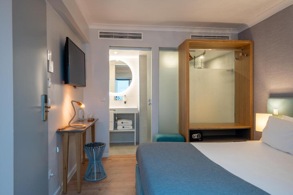 a hotel room with a bed and a television at Reserva FLH Hotels Ericeira in Ericeira