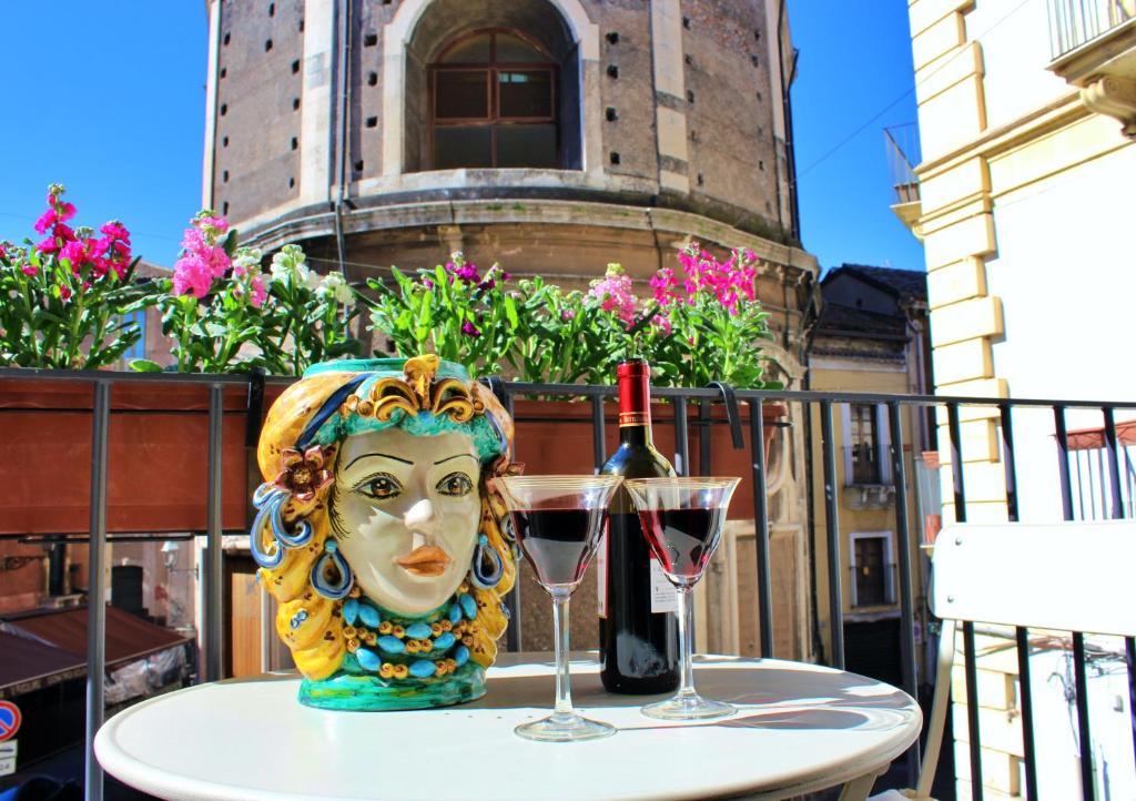 una mesa con máscara y una copa de vino en Barocco B&B, en Catania