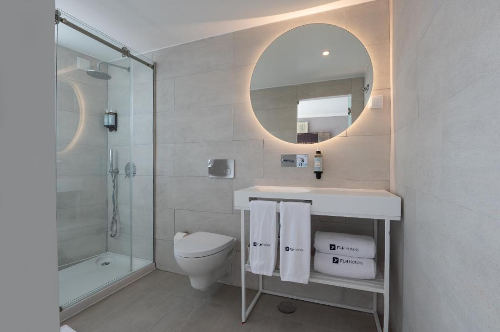 a bathroom with a toilet and a sink and a mirror at Reserva FLH Hotels Ericeira in Ericeira