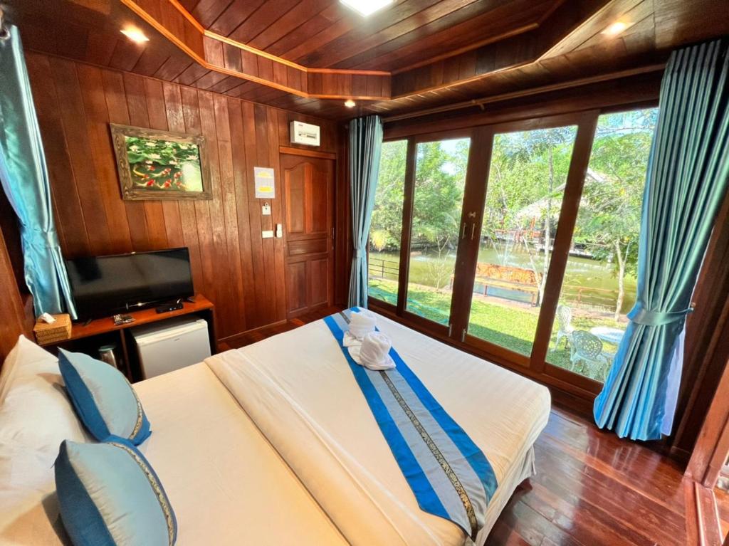 a bedroom with a bed with blue curtains and a tv at บ้านสวนในฝัน-ตลาดน้ำท่าคา in Samut Songkhram