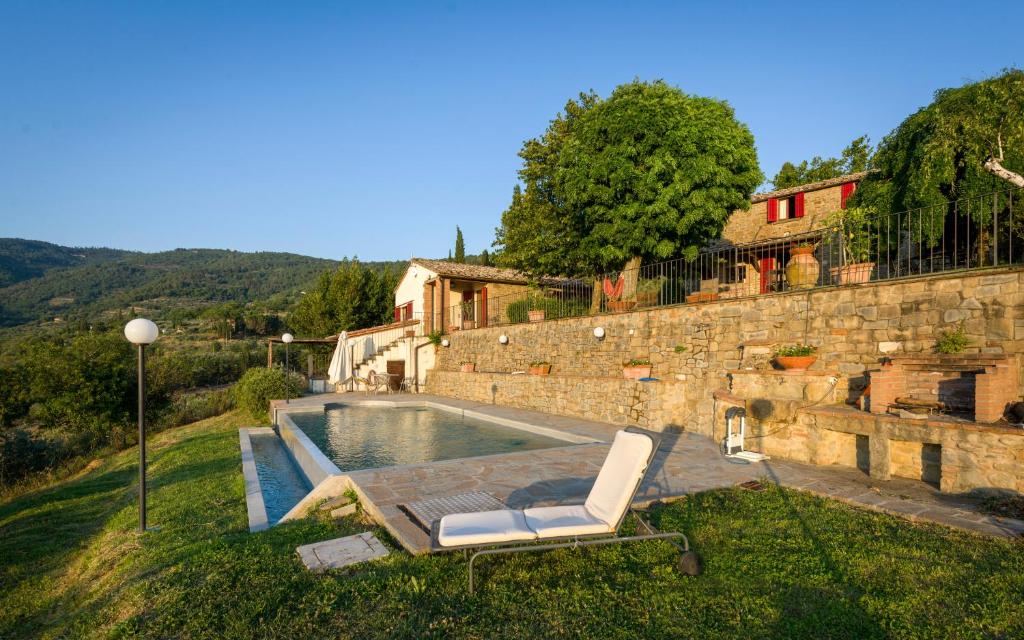 a swimming pool with a lounge chair in front of a building at Agriturismo fringuello - Sofora in Cortona