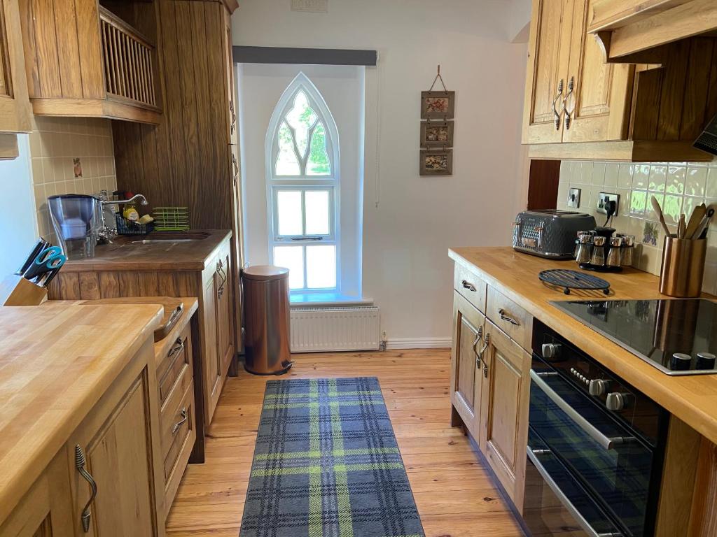 a large kitchen with wooden cabinets and a window at Rathjarney Gatelodge in Wexford