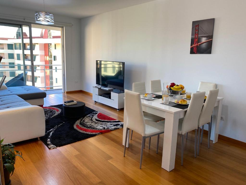 een woonkamer met een tafel, stoelen en een televisie bij Concordia Apartment in Funchal