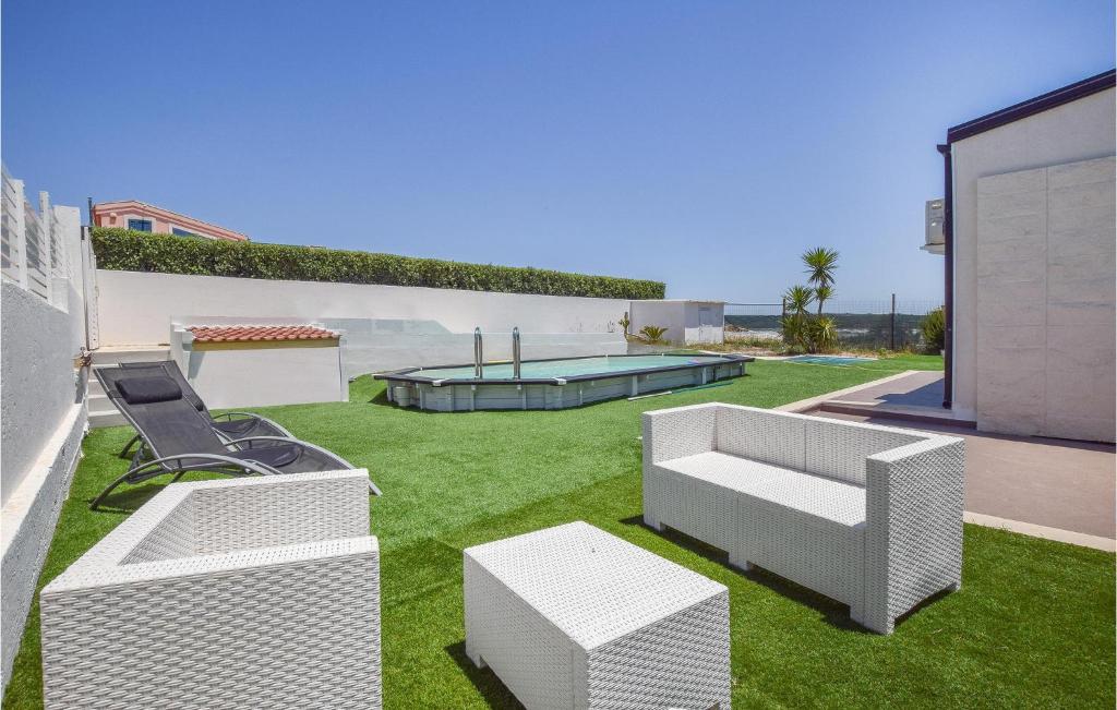 einen Hinterhof mit weißen Möbeln und einem Pool in der Unterkunft Casa Del Mar in Marina di Ragusa