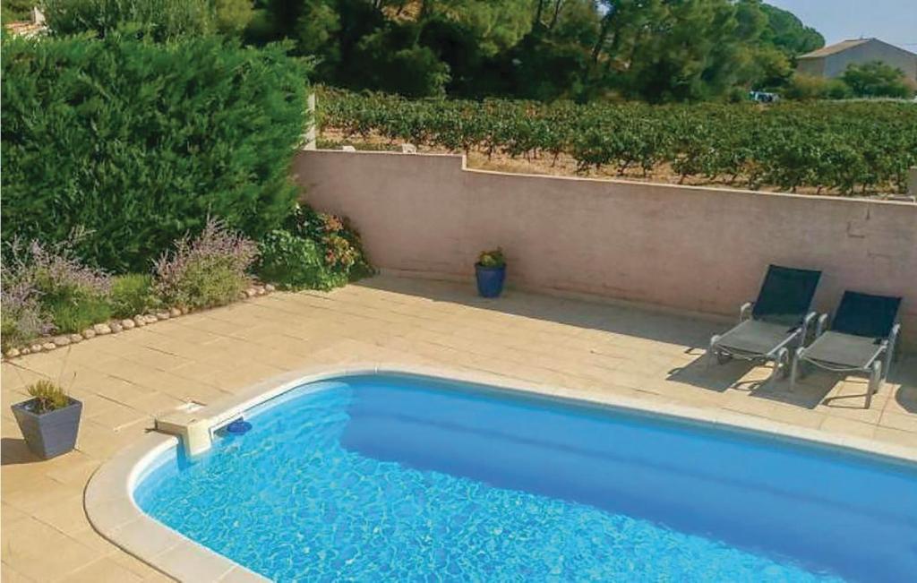 een zwembad met twee stoelen naast een muur bij 3 Bedroom Beautiful Home In Cessenon Sur Orb in Cessenon