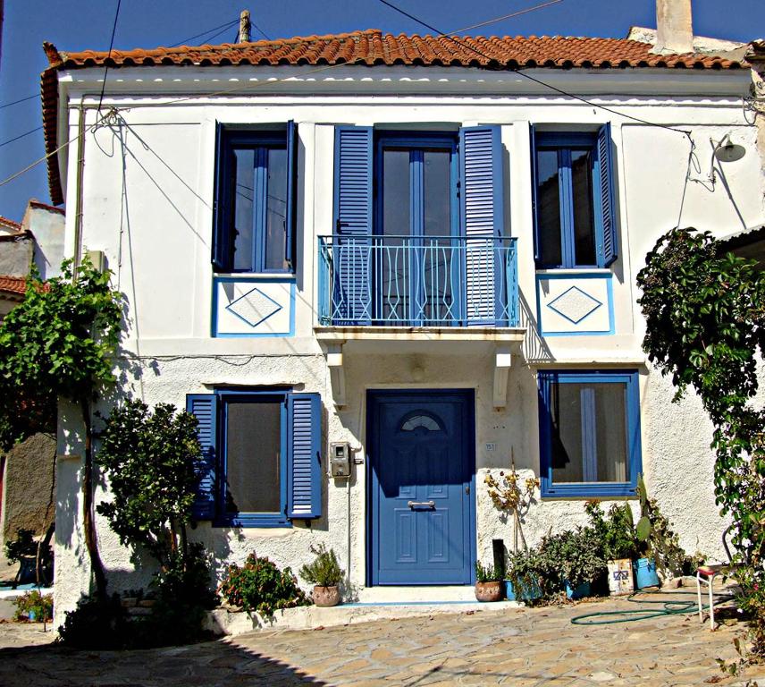 Maison blanche avec volets bleus et porte bleue dans l'établissement Spiti Mili, à Iraion