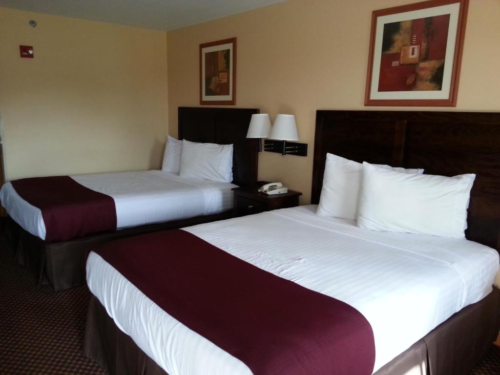 Habitación de hotel con 2 camas con sábanas blancas en Americas Best Value Inn Bryant, en Bryant