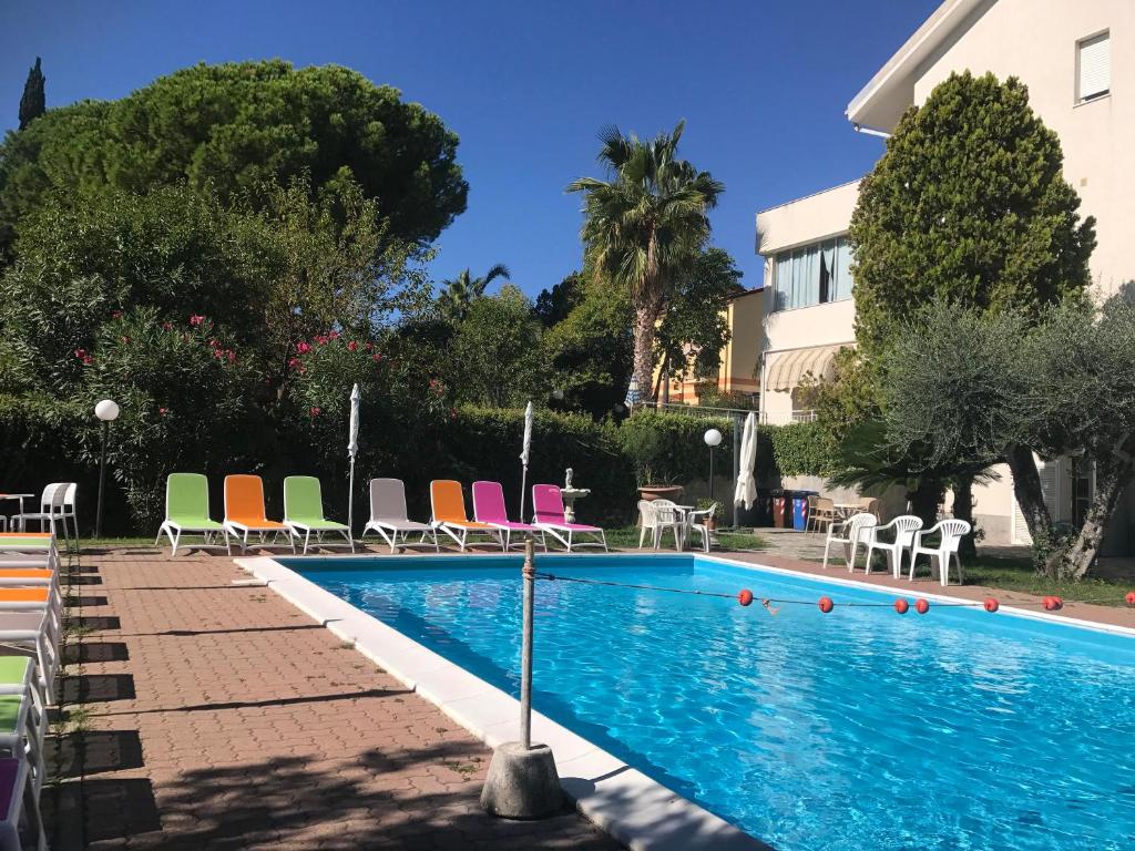 una piscina con sillas coloridas y un edificio en Villa Paola Bilo4 Bis, en Loano