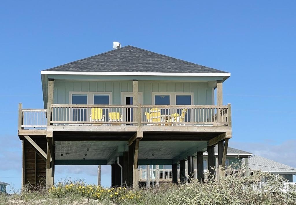 a large house with a deck on the beach at 1 Naut On Call home in Crystal Beach