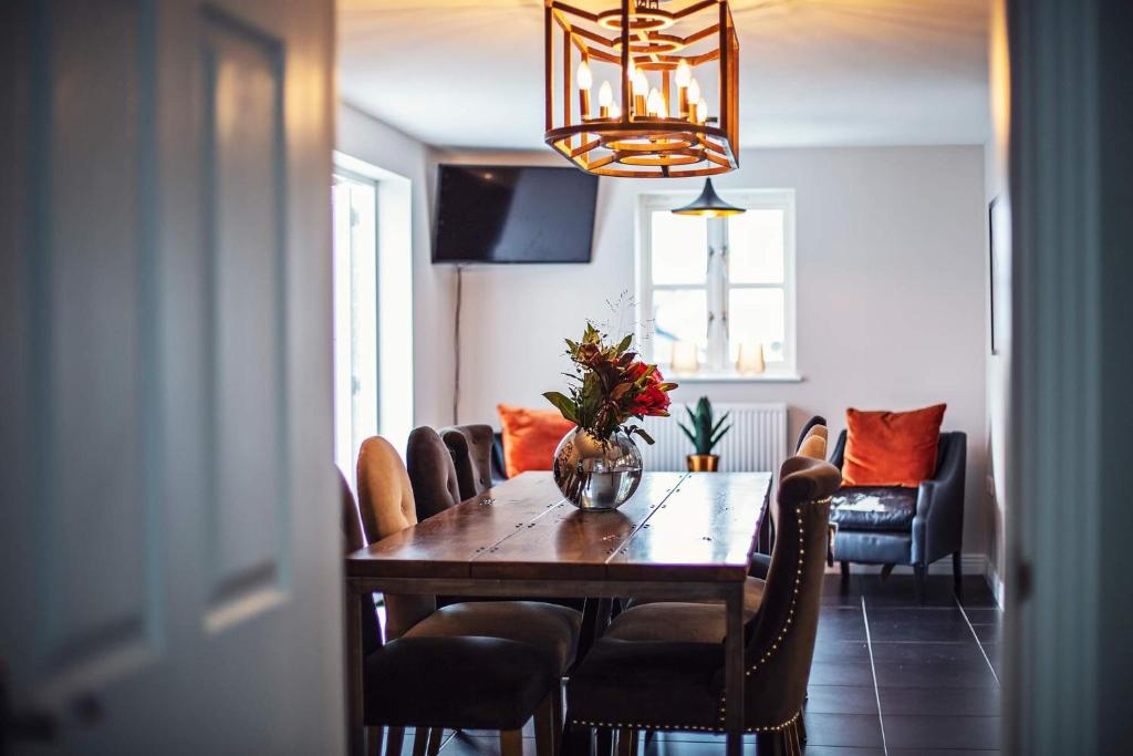 una mesa de comedor con sillas y un jarrón de flores en Larchfield Grange, Luxury House with Stunning Views en Abergavenny