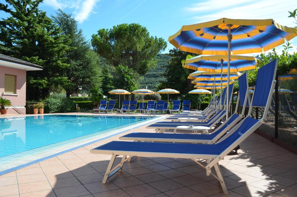 um grupo de cadeiras e guarda-sóis ao lado de uma piscina em SunLake Hotel em Riva del Garda