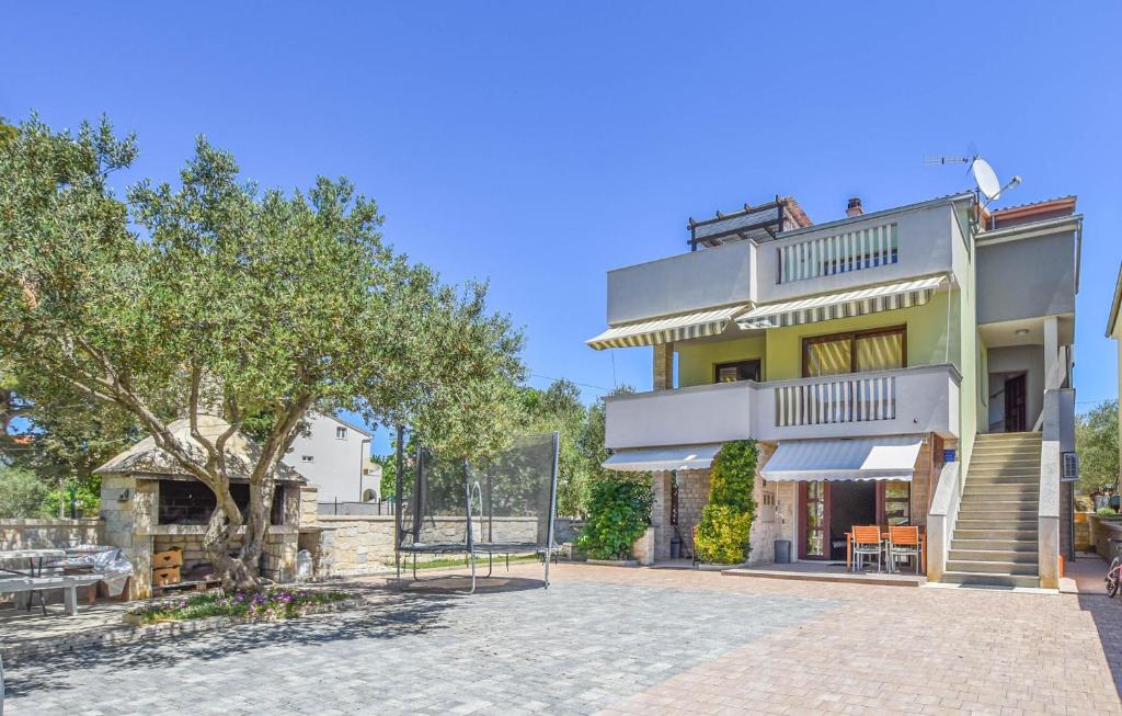 ein großes Haus mit einem Balkon und einem Baum in der Unterkunft Apartments Yelkouan in Biograd na Moru