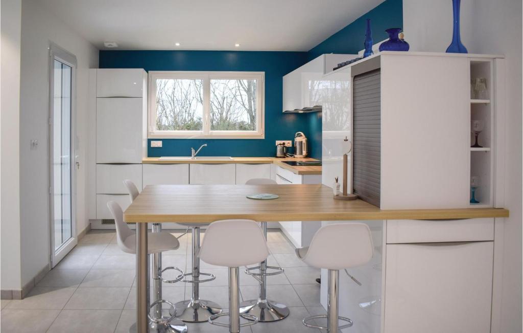 cocina con mesa de madera y armarios blancos en 3 Bedroom Beautiful Home In Matignon, en Matignon