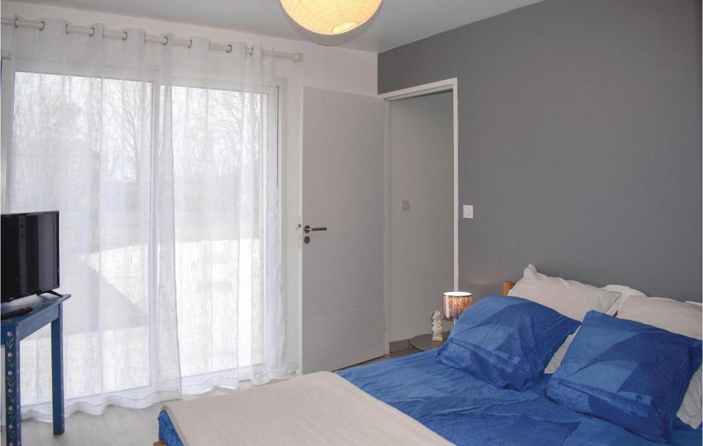 Un dormitorio con una cama con almohadas azules y una ventana en 3 Bedroom Beautiful Home In Matignon, en Matignon