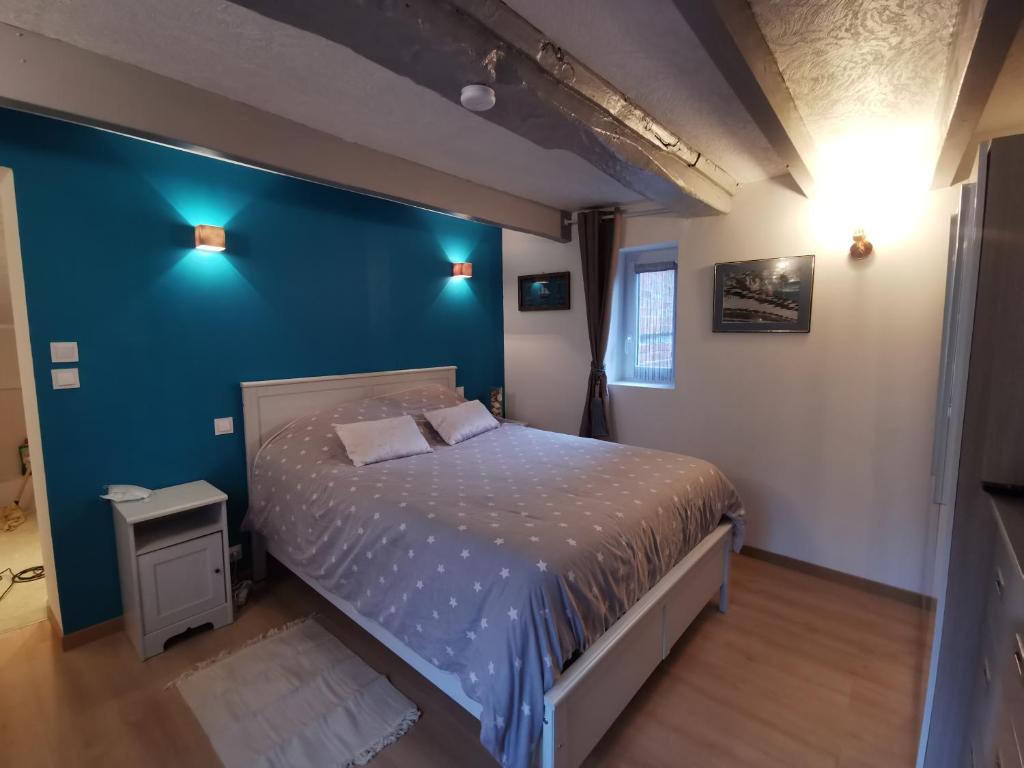 une chambre avec un lit et un mur bleu dans l'établissement Le rez de jardin, à Honfleur