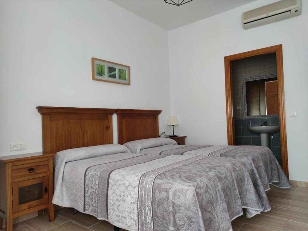 een slaapkamer met een groot bed met een houten hoofdeinde bij Hostal Parador de los Llanos in Torreorgaz