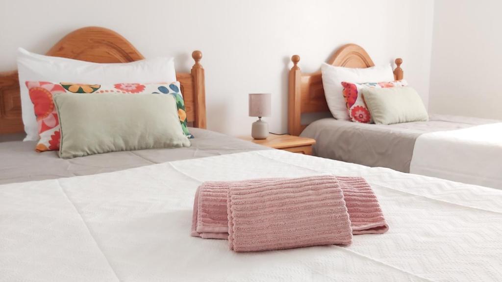 um quarto com 2 camas e uma toalha cor-de-rosa na cama em CASA DA AVÓ - Casa típica em Olhão, perto da Marina em Olhão