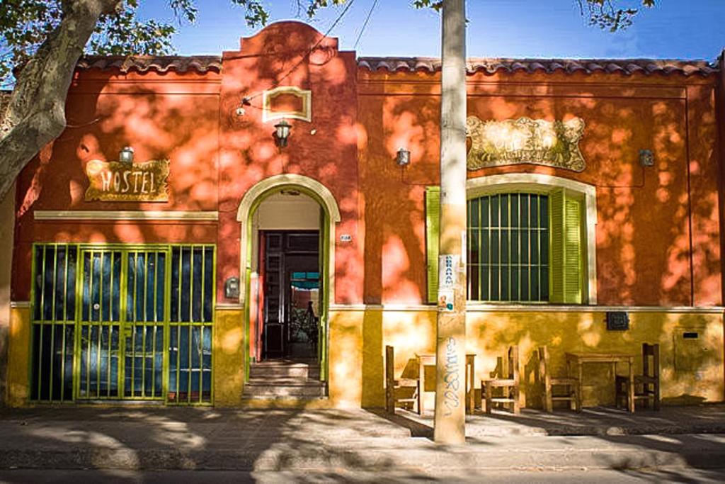 um edifício de tijolos vermelhos com uma porta e uma árvore em Casa Pueblo Hostel em Mendoza