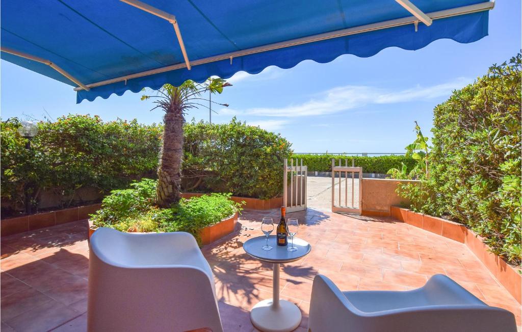 um pátio com uma mesa e cadeiras e um guarda-sol azul em 3 Bedroom Stunning Apartment In Marina Di Ragusa em Marina di Ragusa