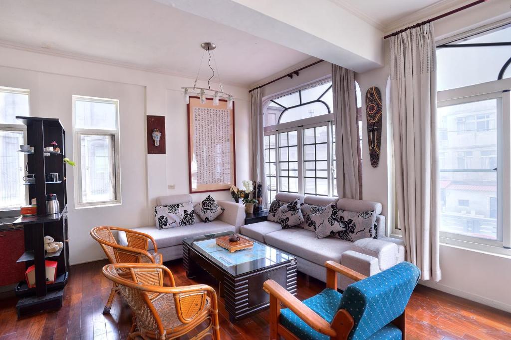 a living room with a couch and chairs and windows at Ding Ding Homestay in Jinhu