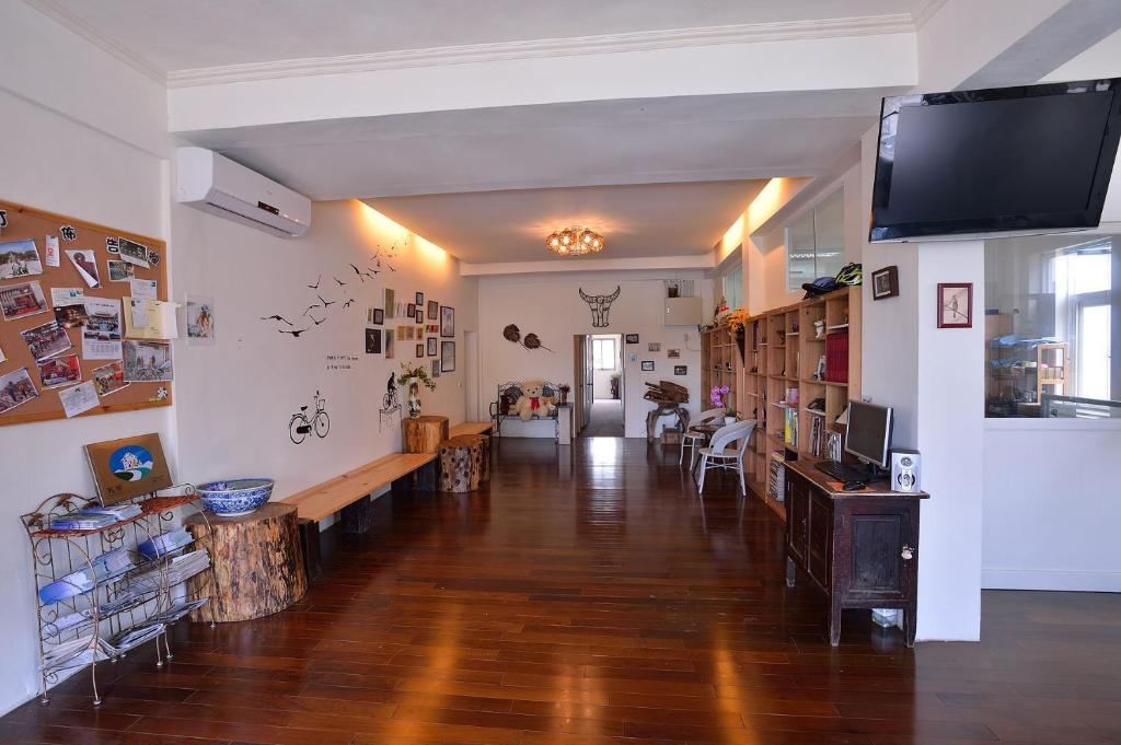 a living room with a wooden floor and a tv on a wall at Ding Ding Homestay in Jinhu