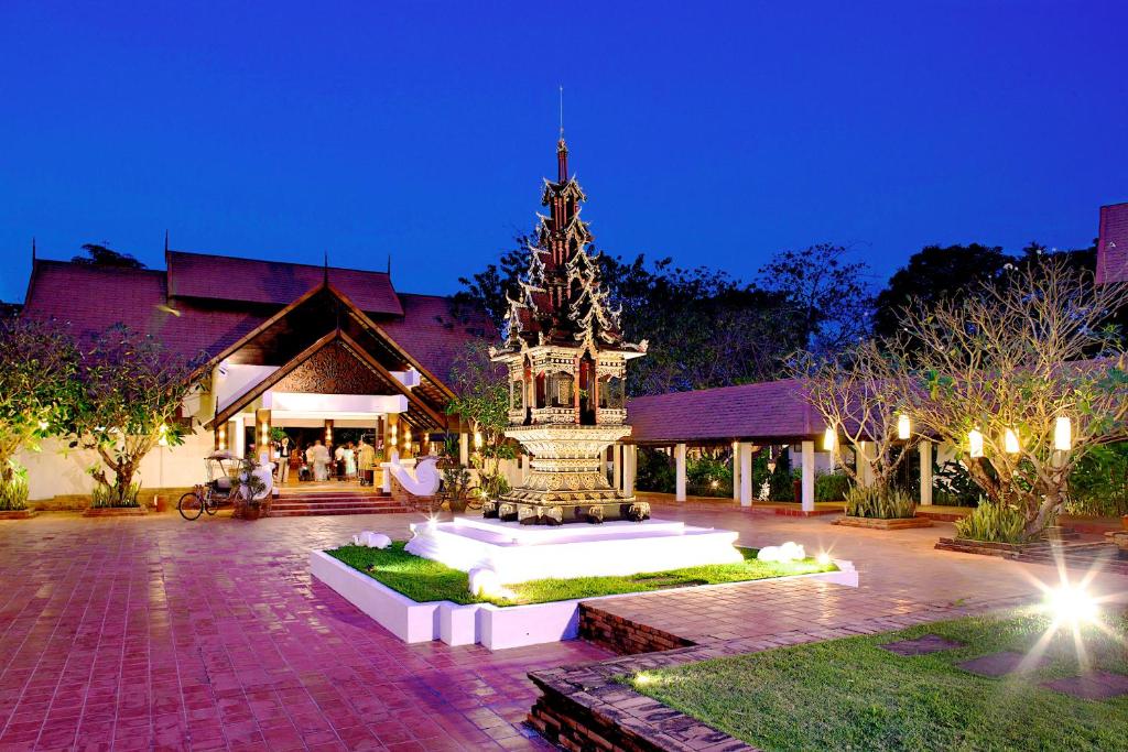 un edificio con un monumento delante de él por la noche en The Legend Chiang Rai Boutique River Resort & Spa, en Chiang Rai
