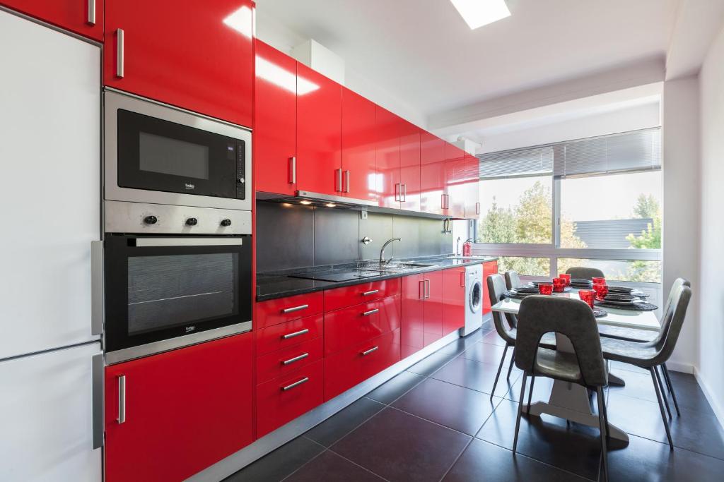 a kitchen with red cabinets and a table with chairs at Feel at home - Free private parking in Braga