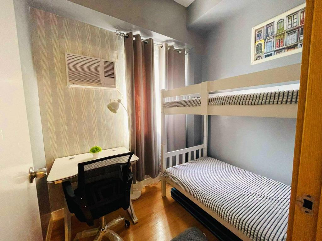 Cette petite chambre comprend 2 lits superposés et un bureau. dans l'établissement 2-Bedroom CK's Corner Staycation Trees Residences, à Manille