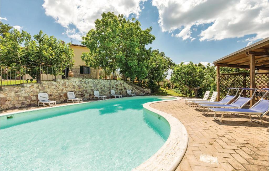 a swimming pool with lounge chairs and a stone wall at 2 Bedroom Amazing Apartment In Giano Dellumbria Pg in Giano dellʼUmbria
