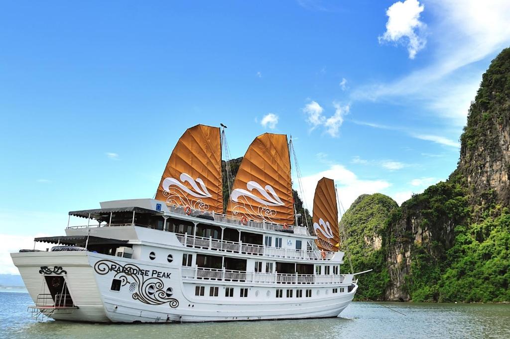a cruise ship in the water next to cliffs at Paradise Peak Cruise in Ha Long