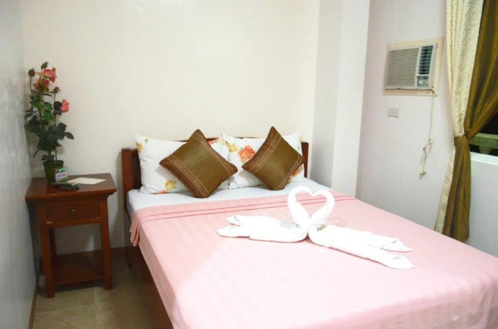 a bedroom with a pink bed with a bow on it at OYO 779 Casa D' Estrella Apartelle in Boracay