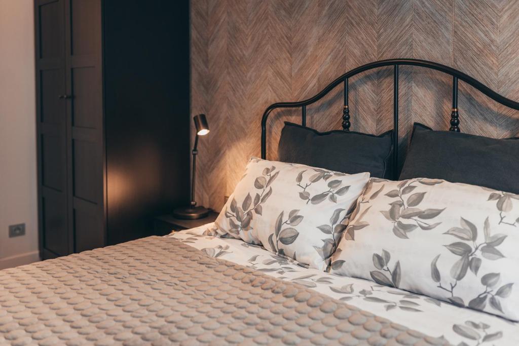 a bed with two pillows and a lamp in a bedroom at Lindens apartments in the heart of the city in Panevėžys