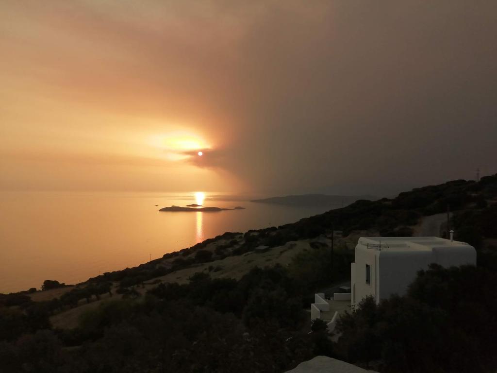 a sunset over a body of water with a building at Aegean Deep Blue Andros Ano Aprovato in Apróvaton