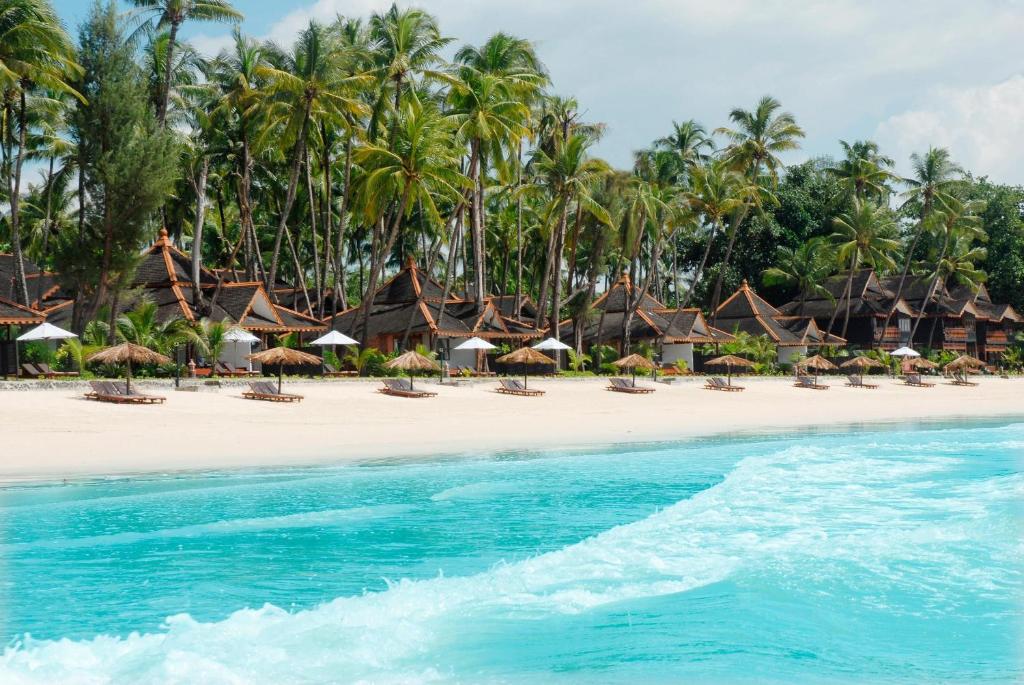 een strand met stoelen, parasols en palmbomen bij Amazing Ngapali Resort in Ngapali