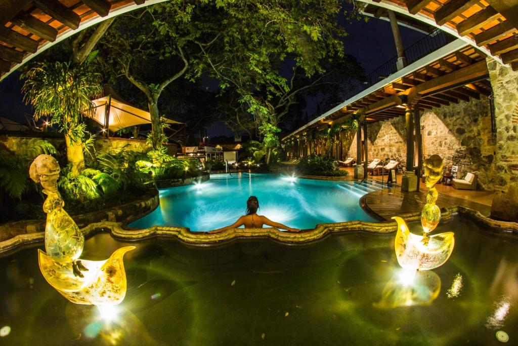 a man laying in a swimming pool at night at Hotel Museo Spa Casa Santo Domingo in Antigua Guatemala