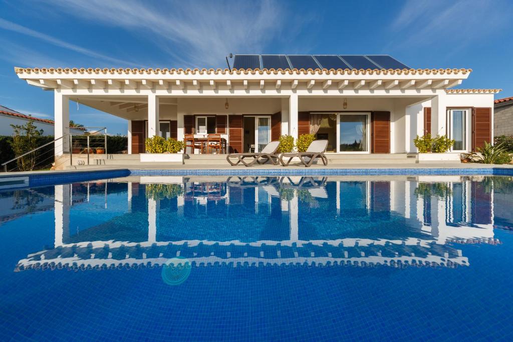 una casa con piscina frente a ella en Villa BINI SOLE, en Binibeca