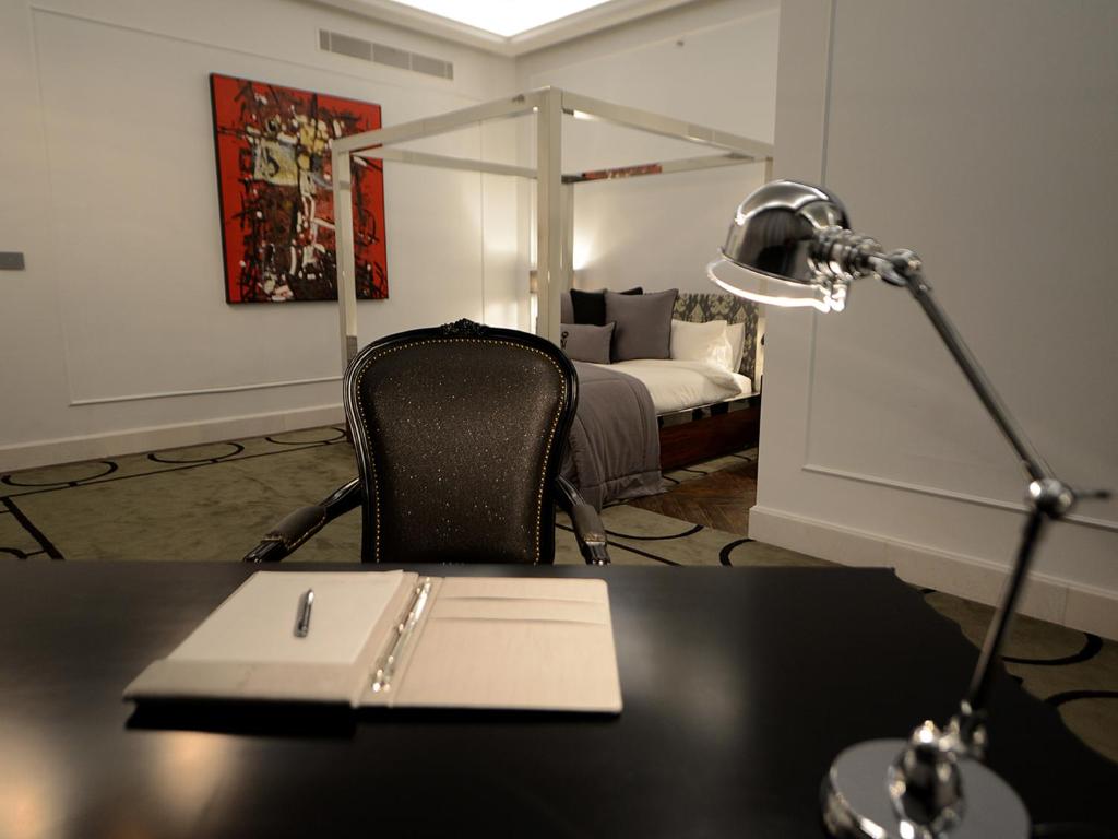 a desk with a lamp and a desk with a bed at The Nishat Hotel in Lahore