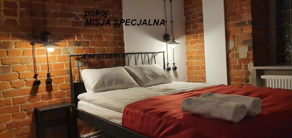 Cama en habitación con pared de ladrillo en Cosy Rooms, en Piotrków Trybunalski