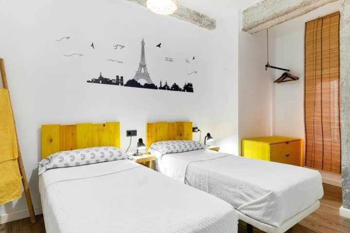 two beds in a bedroom with a picture of the eiffel tower at Alojamiento Simón 2 in Murcia