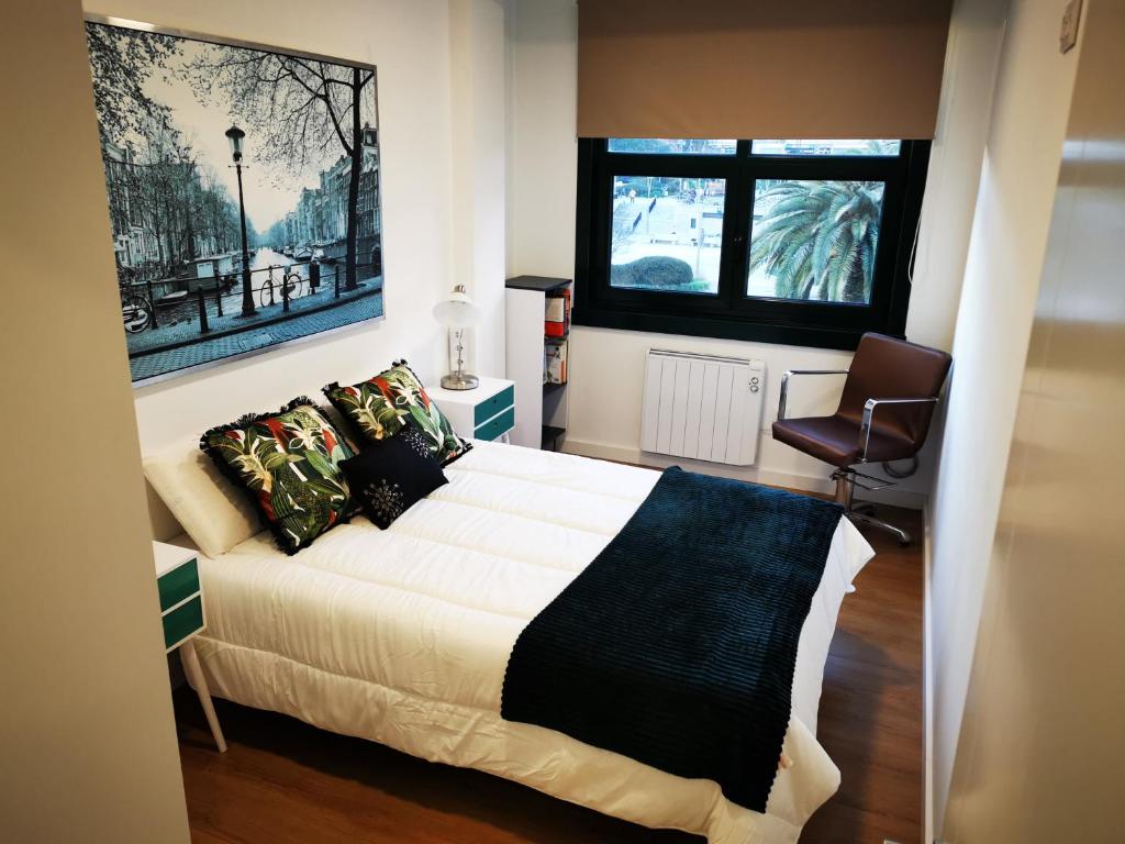 a bedroom with a bed and a chair and a window at Precioso apartamento en A Coruña in A Coruña