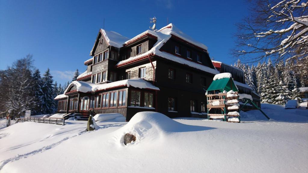 un gran edificio cubierto de nieve en la nieve en Hotel Bouda Jana en Pec pod Sněžkou