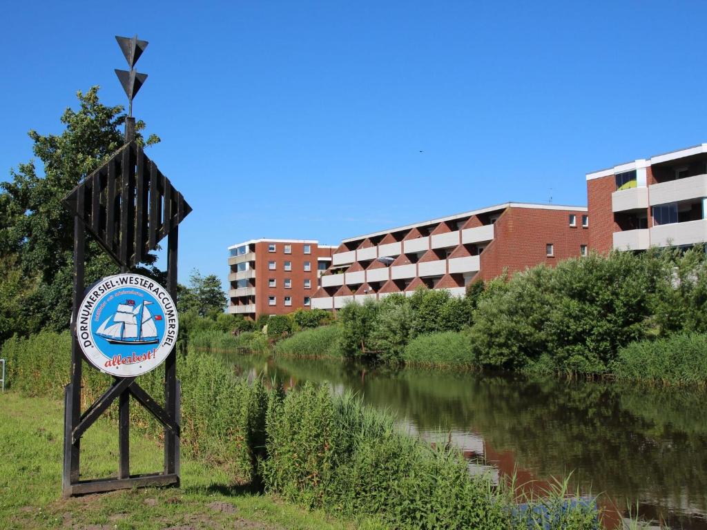 un panneau à côté d'une rivière avec des bâtiments en arrière-plan dans l'établissement Apartment, Dornumersiel, à Dornumersiel