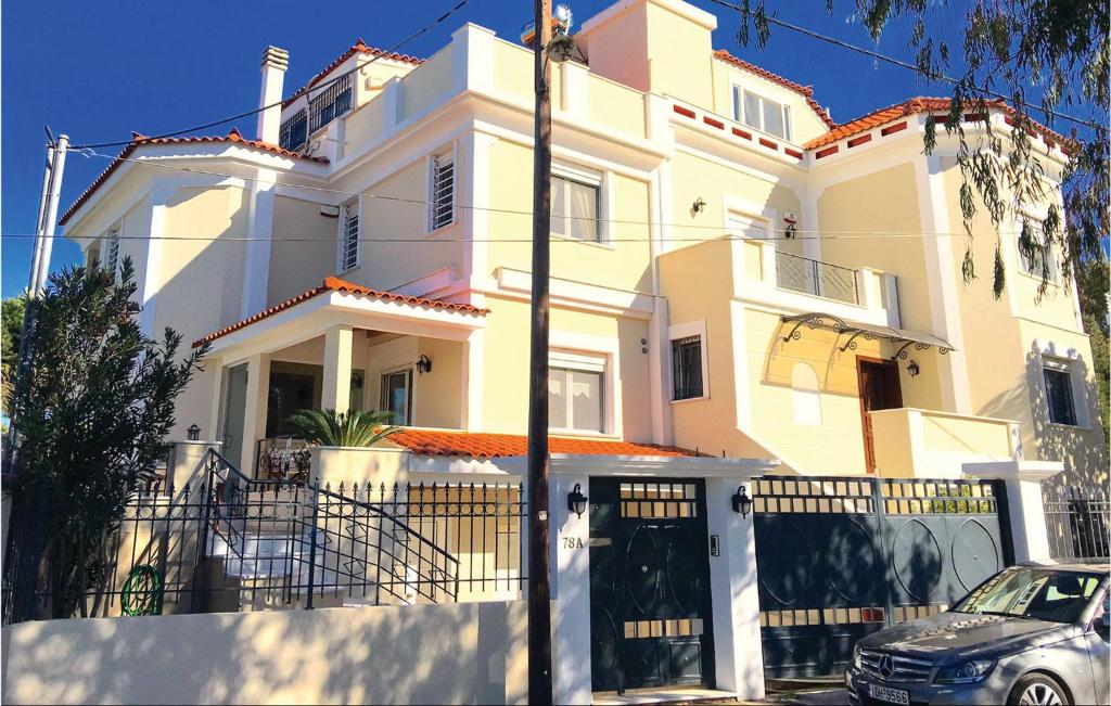 a white house with a car parked in front of it at Nice Home In Nea Makri With Kitchen in Nea Makri
