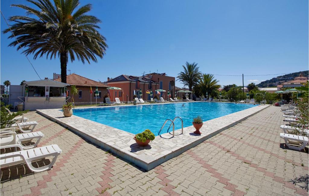 una gran piscina con sillas y palmeras en Casa Borgo 1, en Pietra Ligure